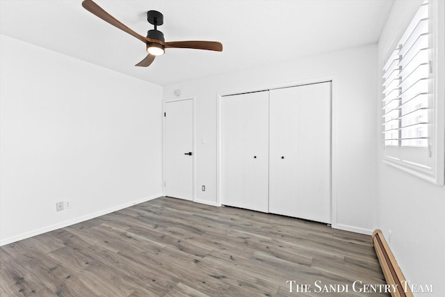 unfurnished bedroom featuring a baseboard radiator, ceiling fan, dark hardwood / wood-style flooring, and a closet