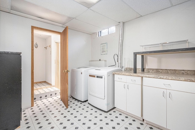 clothes washing area featuring cabinets and washing machine and clothes dryer