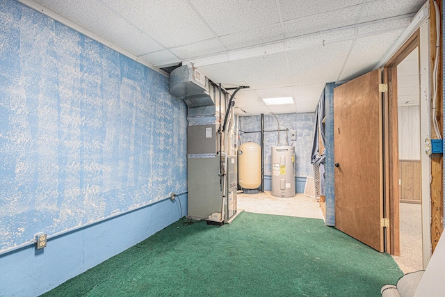 basement featuring heating unit, carpet floors, a paneled ceiling, and electric water heater