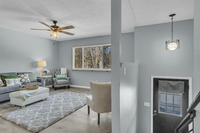 living room with ceiling fan, wood-type flooring, and a textured ceiling