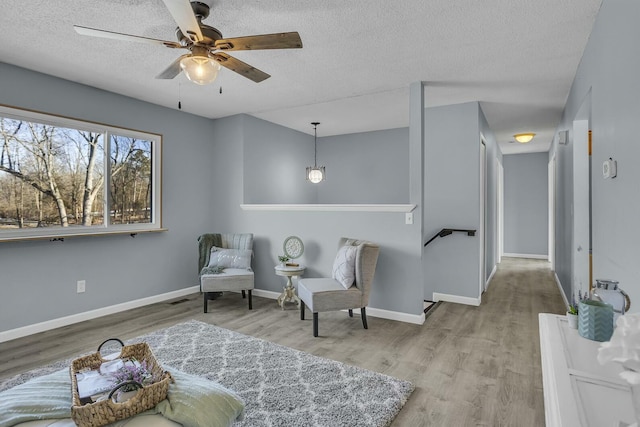 sitting room with hardwood / wood-style flooring, ceiling fan, and a textured ceiling