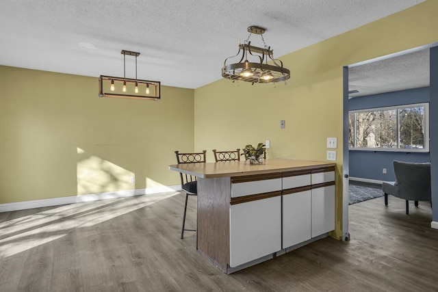 kitchen with pendant lighting, a kitchen bar, hardwood / wood-style floors, and a textured ceiling