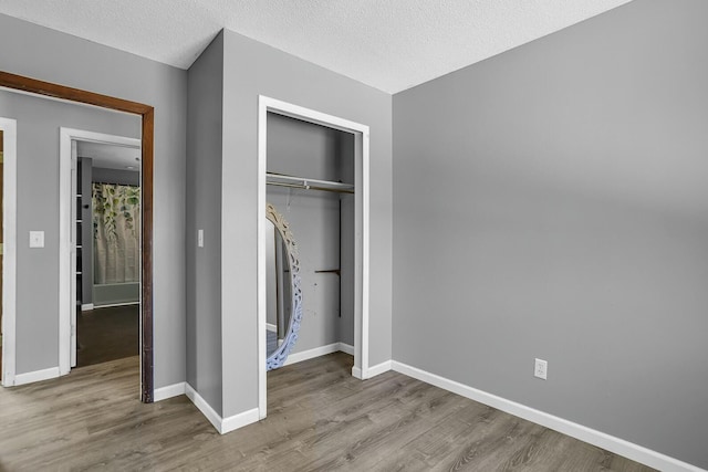 unfurnished bedroom featuring light hardwood / wood-style floors, a closet, and a textured ceiling