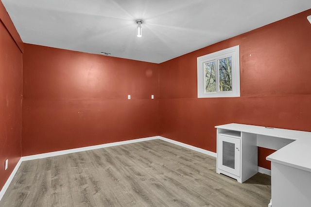 spare room with built in desk and light hardwood / wood-style flooring