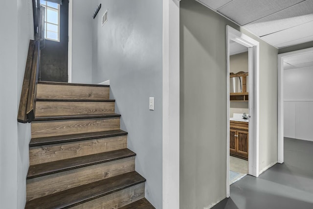 stairway featuring sink and concrete floors