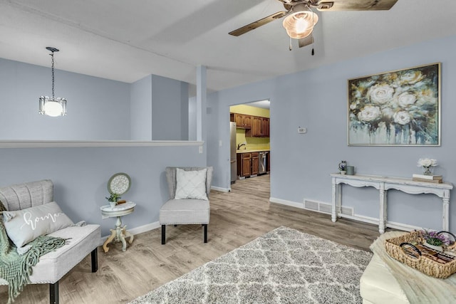 sitting room with sink, ceiling fan, and light hardwood / wood-style flooring