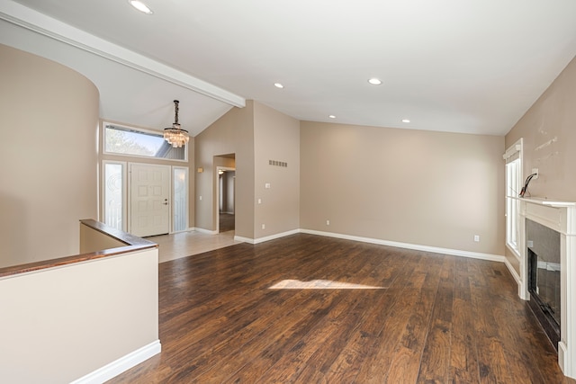 unfurnished living room with dark hardwood / wood-style flooring, vaulted ceiling with beams, and a healthy amount of sunlight