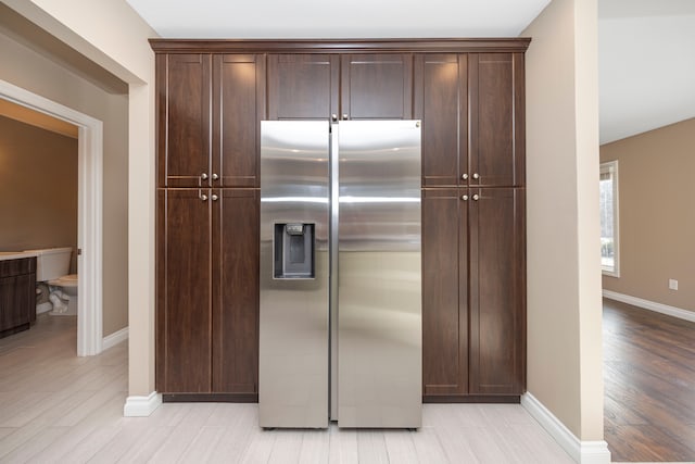 kitchen featuring dark brown cabinetry, stainless steel fridge, and light wood-type flooring