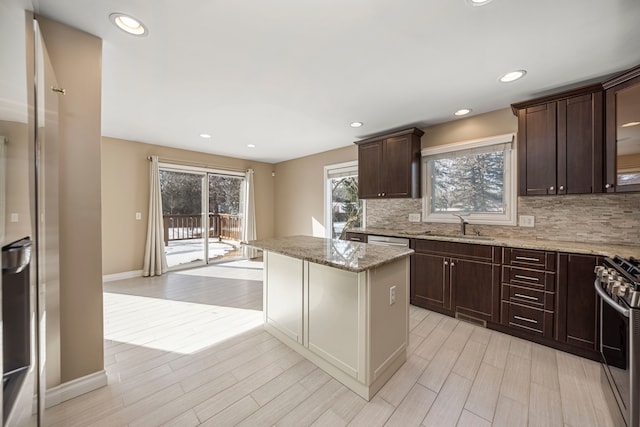 kitchen featuring light stone countertops, a center island, stainless steel stove, and light hardwood / wood-style flooring