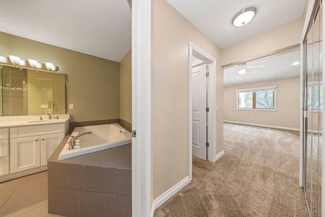 bathroom with vanity, a relaxing tiled tub, and ceiling fan