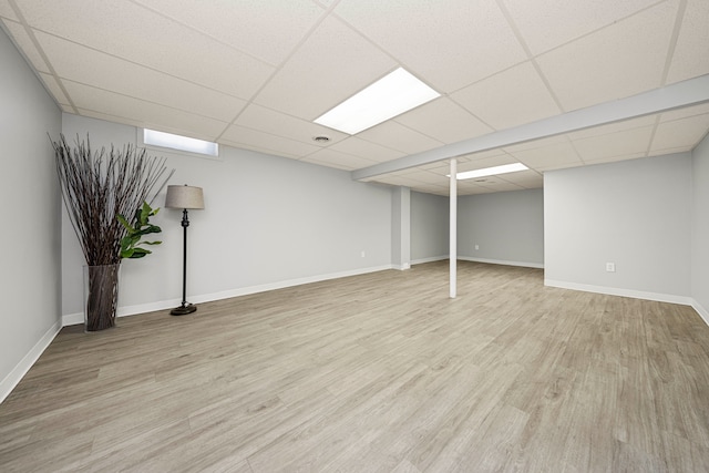 basement featuring a drop ceiling and light hardwood / wood-style flooring