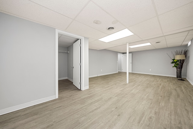 basement featuring a drop ceiling and light hardwood / wood-style floors