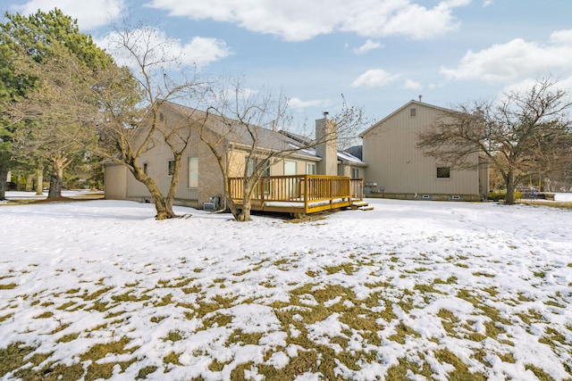 snow covered rear of property with a deck