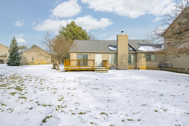 snow covered back of property featuring a wooden deck