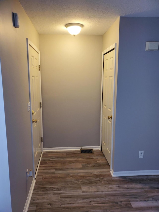 hall with dark hardwood / wood-style flooring and a textured ceiling