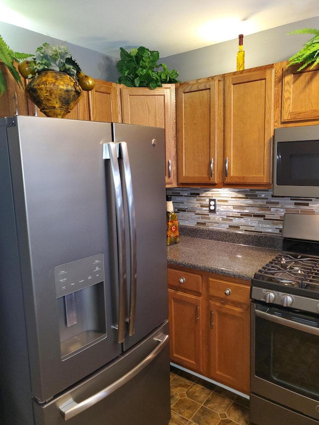 kitchen featuring tasteful backsplash, stainless steel appliances, and dark tile patterned floors