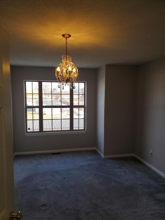 carpeted spare room with a chandelier