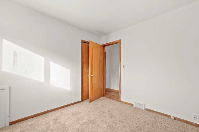 carpeted empty room with visible vents and baseboards