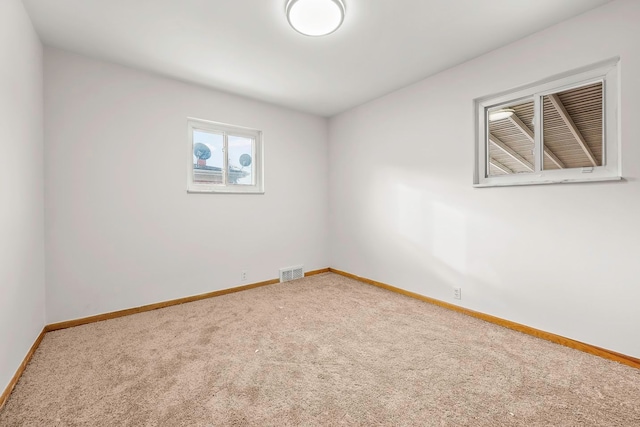 carpeted empty room featuring visible vents and baseboards