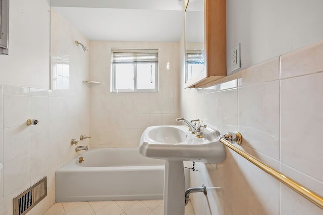 bathroom with tile patterned floors, visible vents, tile walls, and  shower combination