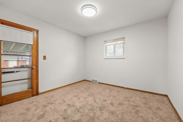 unfurnished room with carpet, visible vents, and baseboards