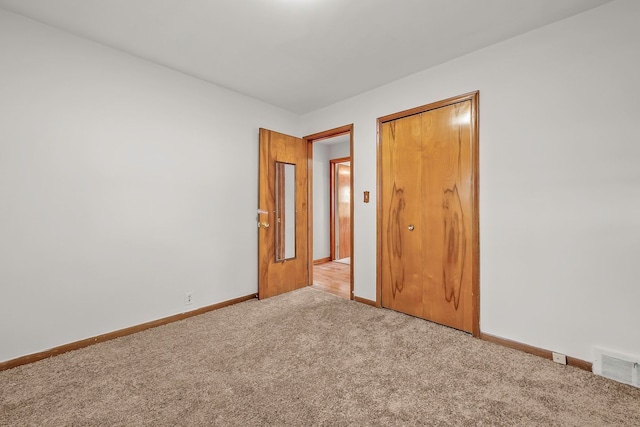 unfurnished bedroom featuring visible vents, carpet floors, baseboards, and a closet