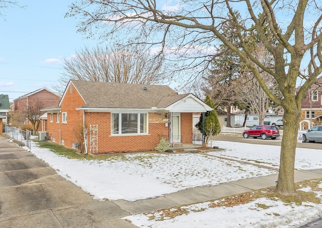 view of front of house featuring cooling unit, fence, brick siding, and a shingled roof