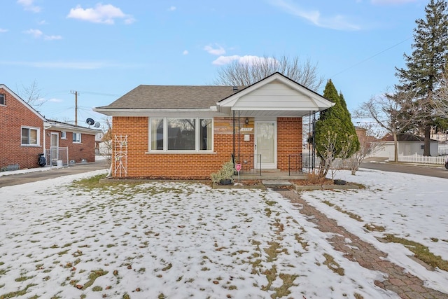 bungalow-style home featuring brick siding and roof with shingles