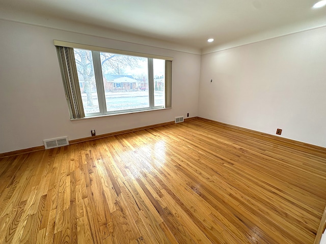 empty room featuring light wood-type flooring, visible vents, baseboards, and recessed lighting