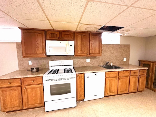 kitchen featuring white appliances, brown cabinetry, and a sink