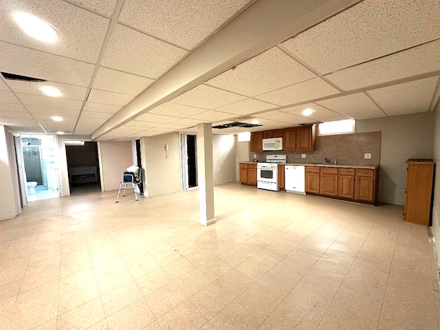 finished basement with a drop ceiling, light floors, visible vents, and a sink