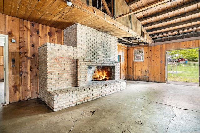 unfurnished living room featuring a brick fireplace, wood ceiling, wooden walls, and concrete floors