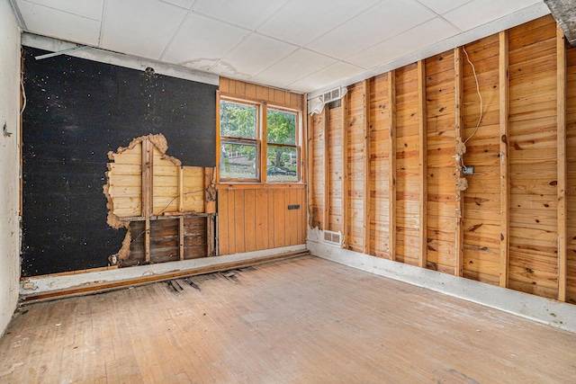 unfurnished room with hardwood / wood-style flooring and wood walls