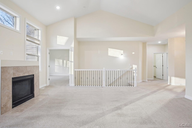 unfurnished living room with a tile fireplace, light carpet, and high vaulted ceiling