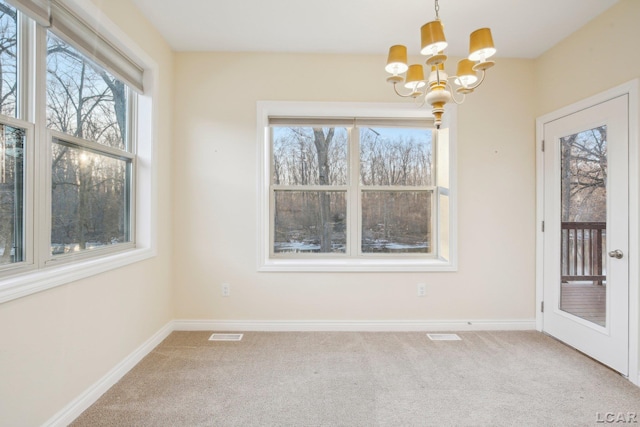 unfurnished dining area featuring carpet and a chandelier