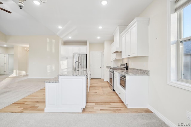 kitchen featuring white cabinetry, sink, a kitchen island with sink, light stone counters, and stainless steel appliances