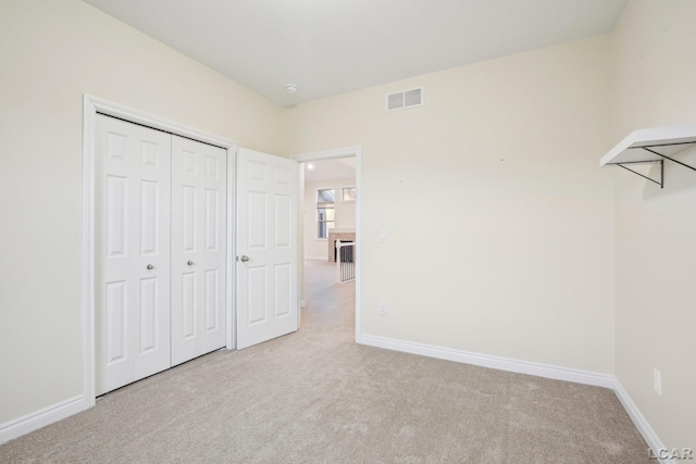 unfurnished bedroom with light colored carpet and a closet