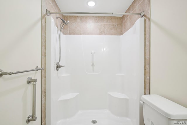 bathroom featuring tiled shower and toilet