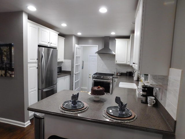 kitchen with wall chimney exhaust hood, white cabinetry, kitchen peninsula, stainless steel appliances, and backsplash