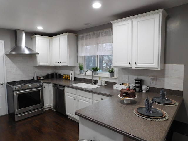 kitchen featuring white cabinets, stainless steel appliances, sink, and wall chimney range hood