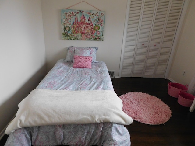 bedroom with dark wood-type flooring and a closet