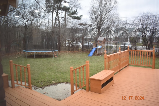 wooden deck featuring a playground, a trampoline, and a lawn