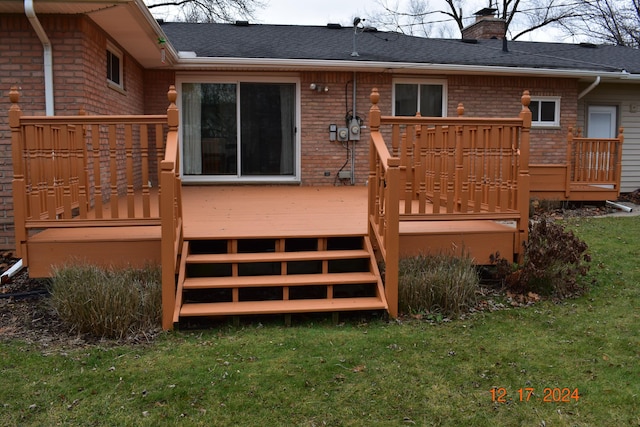 rear view of house with a wooden deck and a lawn