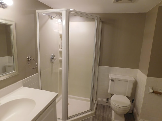 bathroom featuring hardwood / wood-style floors, tile walls, vanity, walk in shower, and toilet