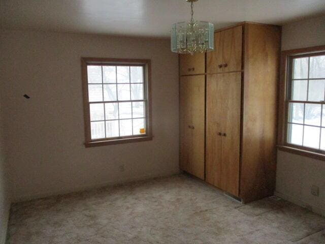 unfurnished bedroom with an inviting chandelier, light carpet, and a closet