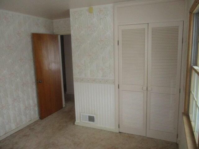 unfurnished bedroom featuring light carpet and a closet