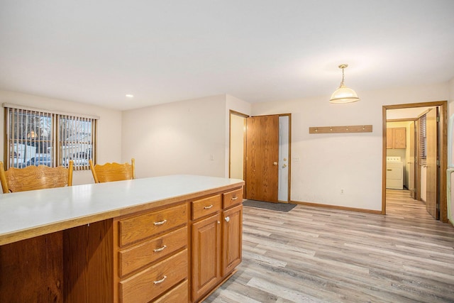 kitchen featuring washer / clothes dryer, pendant lighting, and light wood-type flooring