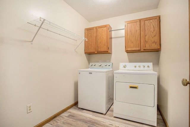 laundry area featuring cabinets, separate washer and dryer, and light hardwood / wood-style floors