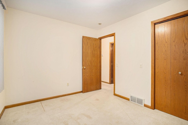 unfurnished bedroom with light carpet and a closet