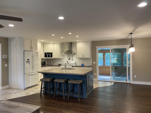 kitchen with white refrigerator with ice dispenser, pendant lighting, white cabinets, and wall chimney exhaust hood